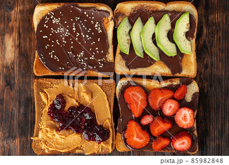 Assortment of sweet sandwiches with chocolate paste, peanut paste and fruit slices 85982848