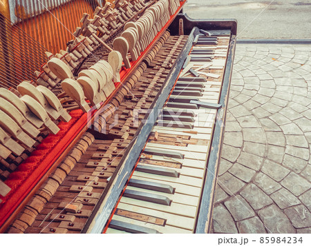 A fragment of an old broken piano with a missing wall and broken keys. Photo with filter applied 85984234
