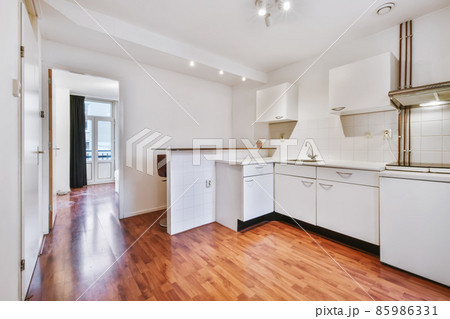Minimalist kitchen with a snow-white kitchen set and wooden floor Minimalist kitchen with a snow-white kitchen set and wooden floor 85986331