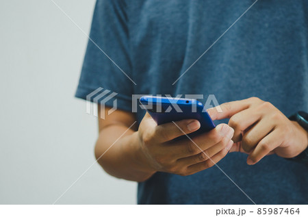 man in a blue shirt is pressing a mobile phone on background. copy space 85987464