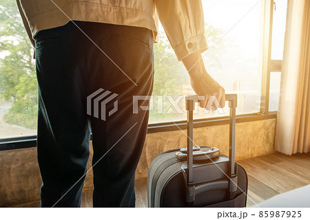 Cropped shot view of tourist woman hand holding her luggage inside the hotel room. Conceptual of travel and vacation. 85987925