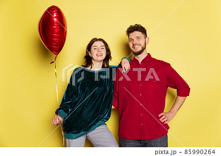 Happy couple, man and woman holding balloons shaped hearts and gift box. Valentine's day celebration. Concept of emotions, love, relations, romantic holidays. Happy couple, man and woman holding balloons shaped hearts and gift box. Valentine's day celebration. Concept of emotions, love, relations, romantic holidays. 85990264
