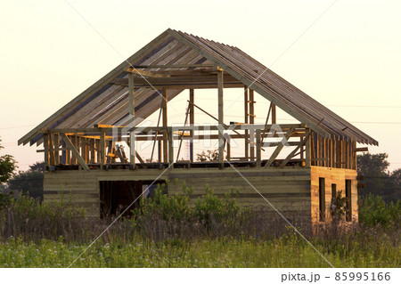 New cottage of natural ecological lumber materials under construction in green field. Wooden walls and steep roof frame. Property, investment, professional building and reconstruction concept. New cottage of natural ecological lumber materials under construction in green field. Wooden walls and steep roof frame. Property, investment, professional building and reconstruction concept. 85995166