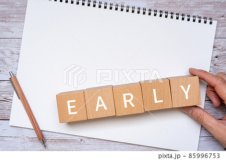 「EARLY」と書かれた積み木、ペン、ノート、人の手 85996753
