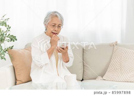 スマホを見る高齢者女性（悩む） 85997898