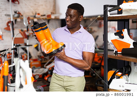 Man chooses rubber boots at garden supply store 86001991