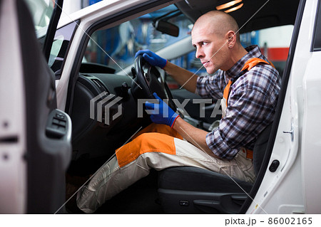 Service engineer in uniform repairs a car steering wheel Service engineer in uniform repairs a car steering wheel 86002165