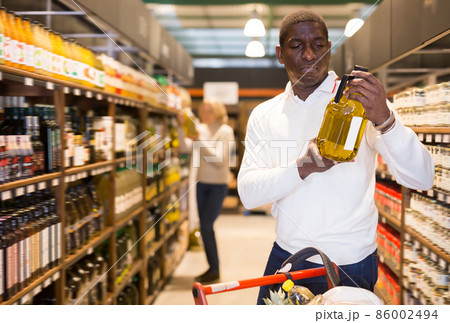 Smiling adult African man standing with bottled oil Smiling adult African man standing with bottled oil 86002494