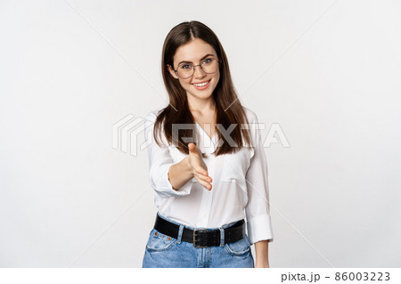 Corporate woman in office extending hand and smiling, handshake, greeting business partner, standing in glasses over white background 86003223