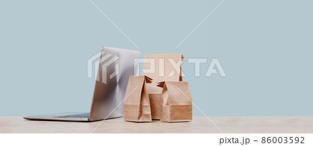 Laptop and paper shopping bags. Packages delivery online orders Laptop and paper shopping bags. Packages delivery online orders 86003592