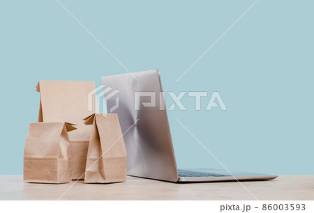 Laptop and paper shopping bags. Packages delivery online orders 86003593