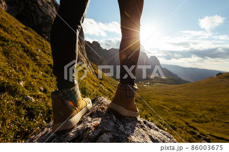 Successful woman hiker legs hiking on sunset alpine mountain peak Successful woman hiker legs hiking on sunset alpine mountain peak 86003675
