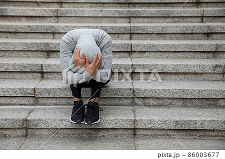 Upset woman sitting alone in city stairs Upset woman sitting alone in city stairs 86003677