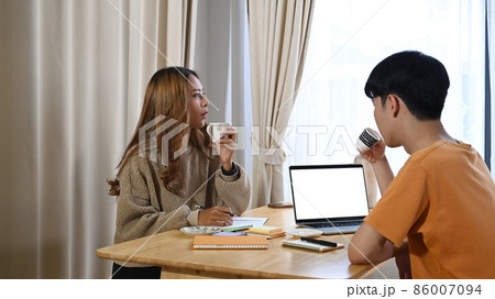 Young asian couple drinking coffee at the morning together in living room. Young asian couple drinking coffee at the morning together in living room. 86007094