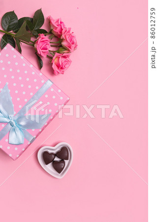 Pink gift box with blue bow on pink background with pink roses and chocolate sweets . Valentine's Day. Mother's Day. 86012759
