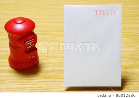 木目のテーブルに置いた郵便ポスト形の貯金箱と郵便封筒(コピースペース有り) 木目のテーブルに置いた郵便ポスト形の貯金箱と郵便封筒(コピースペース有り) 86012836