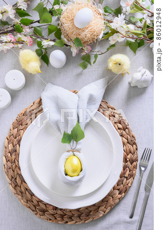 Easter table setting with yellow chick,decorations, fresh flowers and eggs. Elegance dinner at home. Close up. 86012948