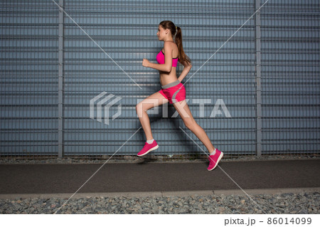 Running woman. jogging against the background of a gray wall Running woman. jogging against the background of a gray wall 86014099