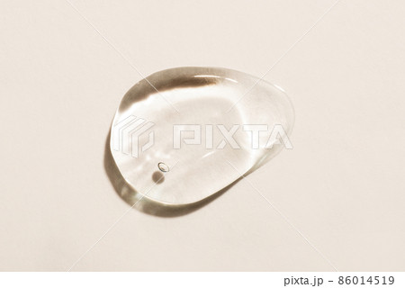 Transparent hyaluronic acid gel drop on a beige background. 86014519