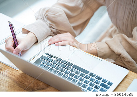 ノートパソコンを使いながらメモをとる女性の手元【パーツカット】 86014639