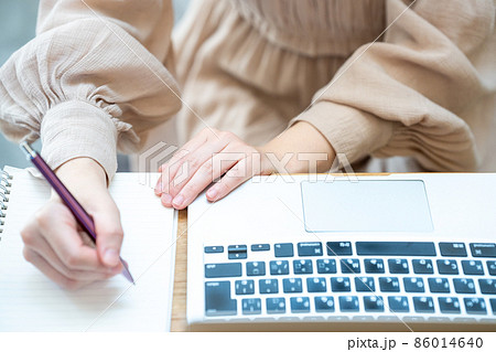 ノートパソコンを使いながらメモをとる女性の手元【パーツカット】 86014640