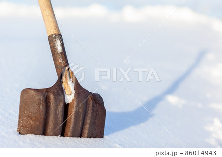 Metal shovel stuck with snow close-up. Snow removal in winter after a snowfall. Clearing snow in the home area. Metal shovel stuck with snow close-up. Snow removal in winter after a snowfall. Clearing snow in the home area. 86014943