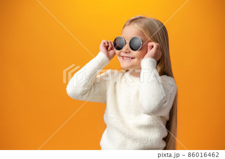 Little girl wearing sunglasses on a yellow background 86016462