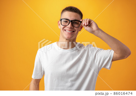 Portrait of a teen boy smiling against yellow background 86016474