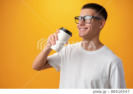 Teen boy with glasses and coffee to go on yellow 86016547