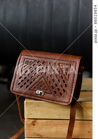 small brown women's leather bag with a carved pattern. selective focus small brown women's leather bag with a carved pattern. selective focus 86019954