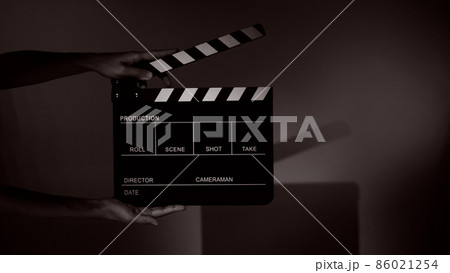 Blurry images of movie slate or clapper board. Hand holds empty film making clapperboard on color background in studio for film movie shooting or recording. Film slate for Youtuber video production. 86021254