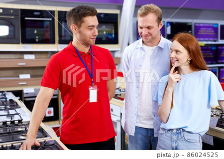 pleasant guy consultor in red uniform showing hog to couple came to make purchase 86024525