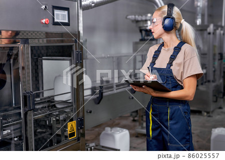 Female worker hold inspection control, in protective workwear working in factory Female worker hold inspection control, in protective workwear working in factory 86025557