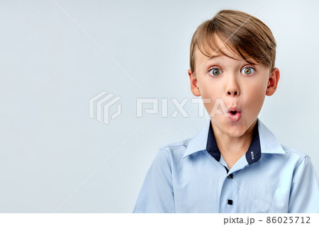 funny school boy with opened mouth, looks at camera trying to remember something 86025712