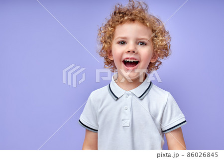 Cheerful little kid with curly hair laughing after hearing funny joke from friend. 86026845