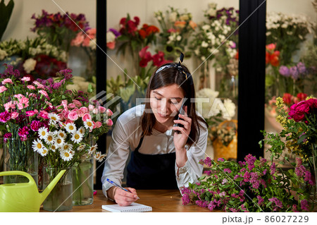 confident beautiful flower shop owner talking on phone with client. Small business. confident beautiful flower shop owner talking on phone with client. Small business. 86027229