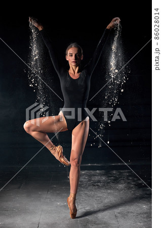 Ballet dancer dancing with flour on black studio background. Dancer in black bodysuit 86028014