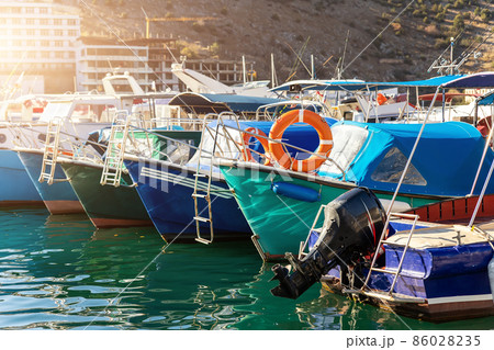 Row of many small old wooden vintage colorful bright fishing ships moored at fisherman village marina clear water bay on bright sunny day. Sea harbor with traditional retro vessels background 86028235