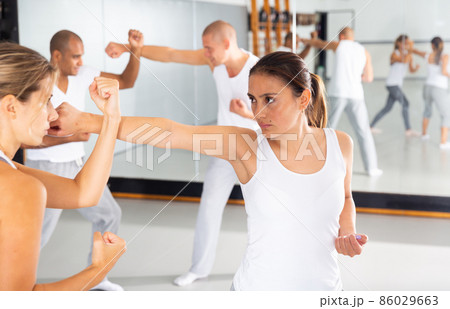 Hispanic woman practicing self defense moves with female partner 86029663