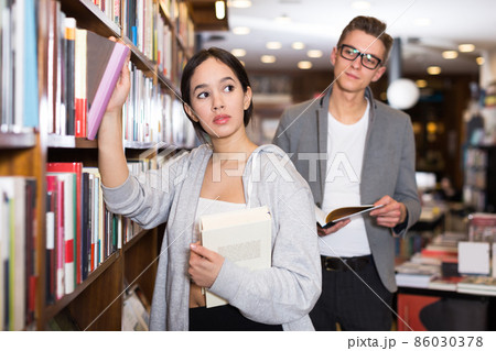 female choosing books attracted attention of guy female choosing books attracted attention of guy 86030378