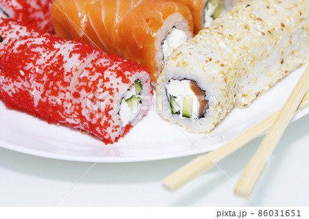 Sushi rolls wrapped in nori. Sushi sticks next to the rolls. Traditional Japanese food. Sushi rolls wrapped in nori. Sushi sticks next to the rolls. Traditional Japanese food. 86031651
