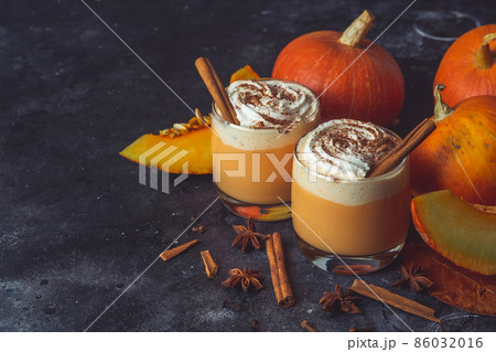 Pumpkin latte drink. Autumn coffee with spicy pumpkin flavor and cream on a dark background. Seasonal Fall Drinks for Halloween and Thanksgiving Pumpkin latte drink. Autumn coffee with spicy pumpkin flavor and cream on a dark background. Seasonal Fall Drinks for Halloween and Thanksgiving 86032016