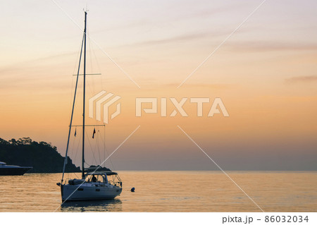 Yacht at sunset. A yacht in the sea bay against the backdrop of a beautiful sunset. Travel and romance concept. 86032034