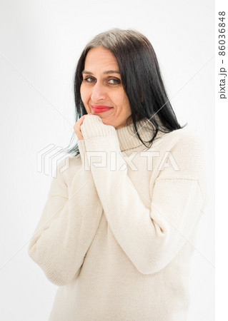Middle aged woman starting getting grey-haired is posing in studio in sweater on white background, face skin care beauty, middle age skincare cosmetics, cosmetology concept Middle aged woman starting getting grey-haired is posing in studio in sweater on white background, face skin care beauty, middle age skincare cosmetics, cosmetology concept 86036848