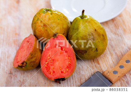 Whole and halved tropical apple guavas on wooden background 86038351