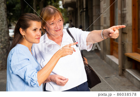 Elderly woman pointing direction to young female Elderly woman pointing direction to young female 86038578