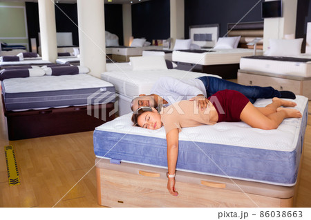 Portrait of young tired people sleeping on modern orthopedic mattress in furniture showroom Portrait of young tired people sleeping on modern orthopedic mattress in furniture showroom 86038663