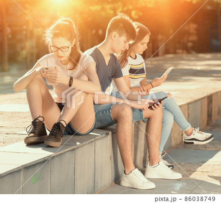 Teenagers with phones absorbed in online communication Teenagers with phones absorbed in online communication 86038749