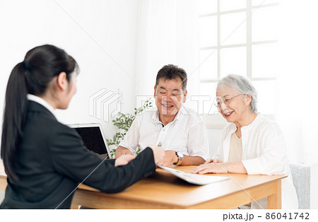パソコンで説明するスーツ姿の女性と高齢者夫婦 86041742