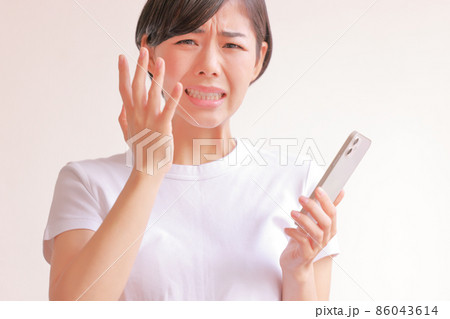 スマホを持ち悔しい表情の女性1 86043614